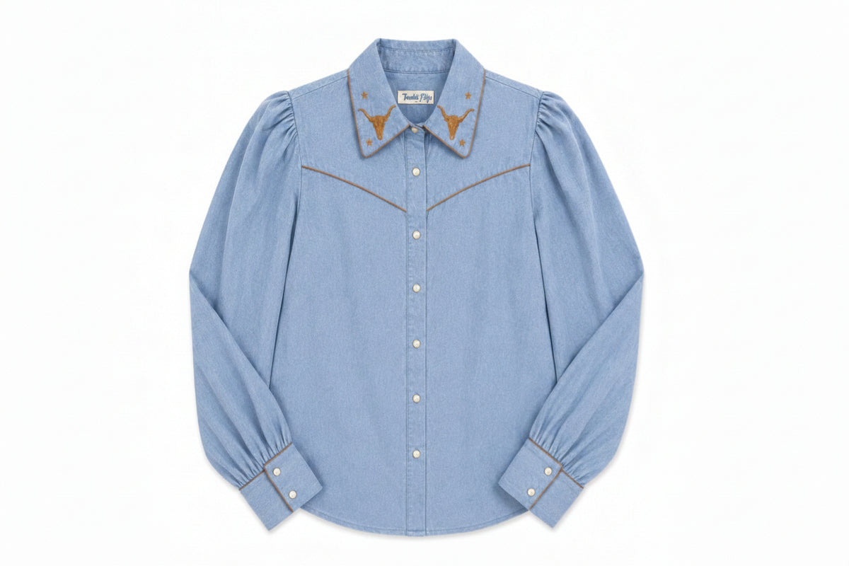 A light blue denim long-sleeve western-style shirt with gold embroidered details on the collar and chest, shown flat against a white background.