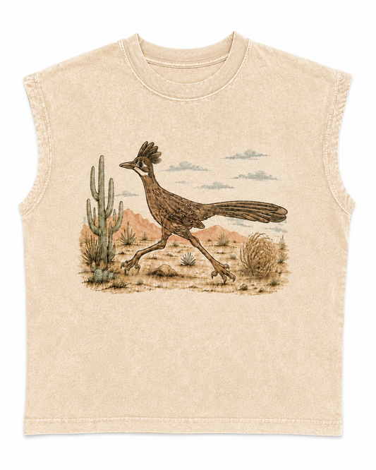 A sleeveless crewneck t-shirt in a light beige, washed cotton fabric, featuring a graphic print of a desert roadrunner walking past a saguaro cactus under a cloudy sky.