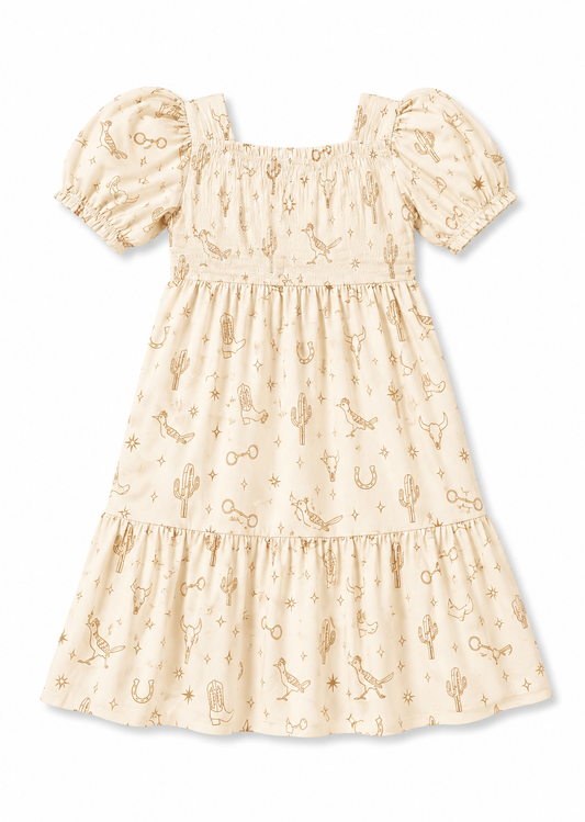 A cream-colored tiered dress with puff sleeves and an allover gold western-themed print featuring cacti, horseshoes, and cowboy boots, shown against a plain white background.