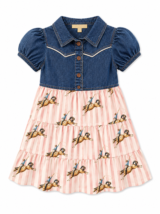 A girl's two-tone dress with a blue denim bodice featuring white western-style stitching and puff sleeves, paired with a tiered pink and white striped skirt printed with bucking horse