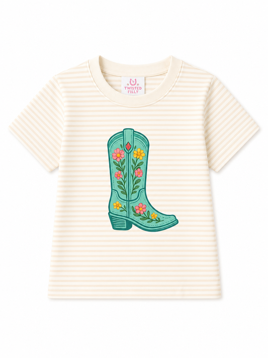 A cream and beige horizontally striped short-sleeve t-shirt featuring a colorful embroidered turquoise cowboy boot with floral details on the front, displayed flat against a white background.