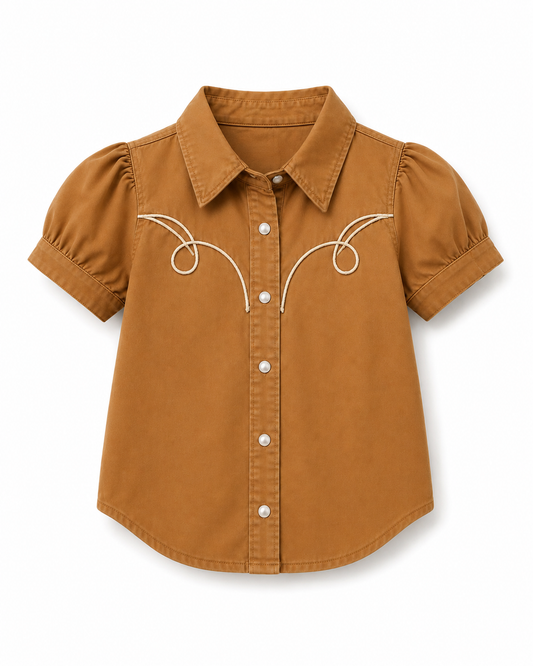 A toddler's short-sleeve button-down shirt in a warm camel brown color, featuring white embroidered swirl details on the chest and white buttons, shown against a plain white background.